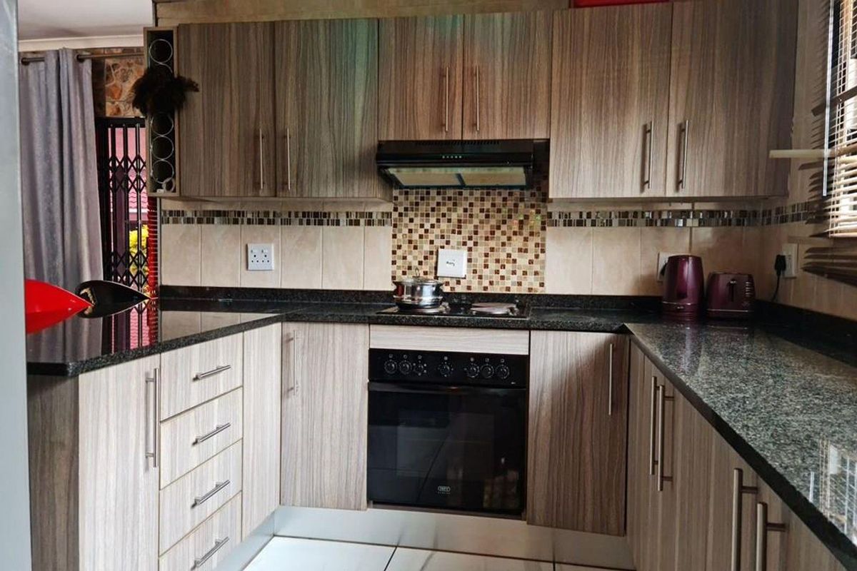 A functional kitchen featuring wood-grain cabinetry, granite countertops, a built-in oven, and a mosaic tile backsplash.
