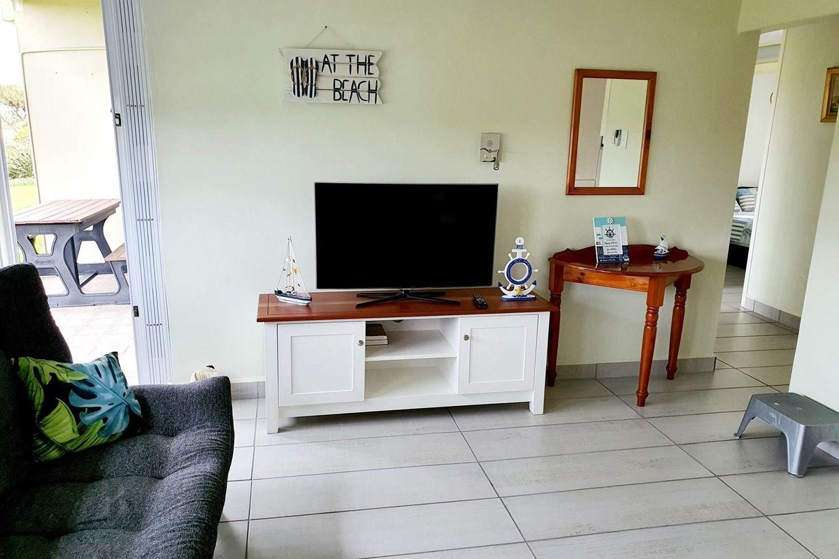 A living room area featuring tiled flooring and a sliding door leading to an outdoor patio space.