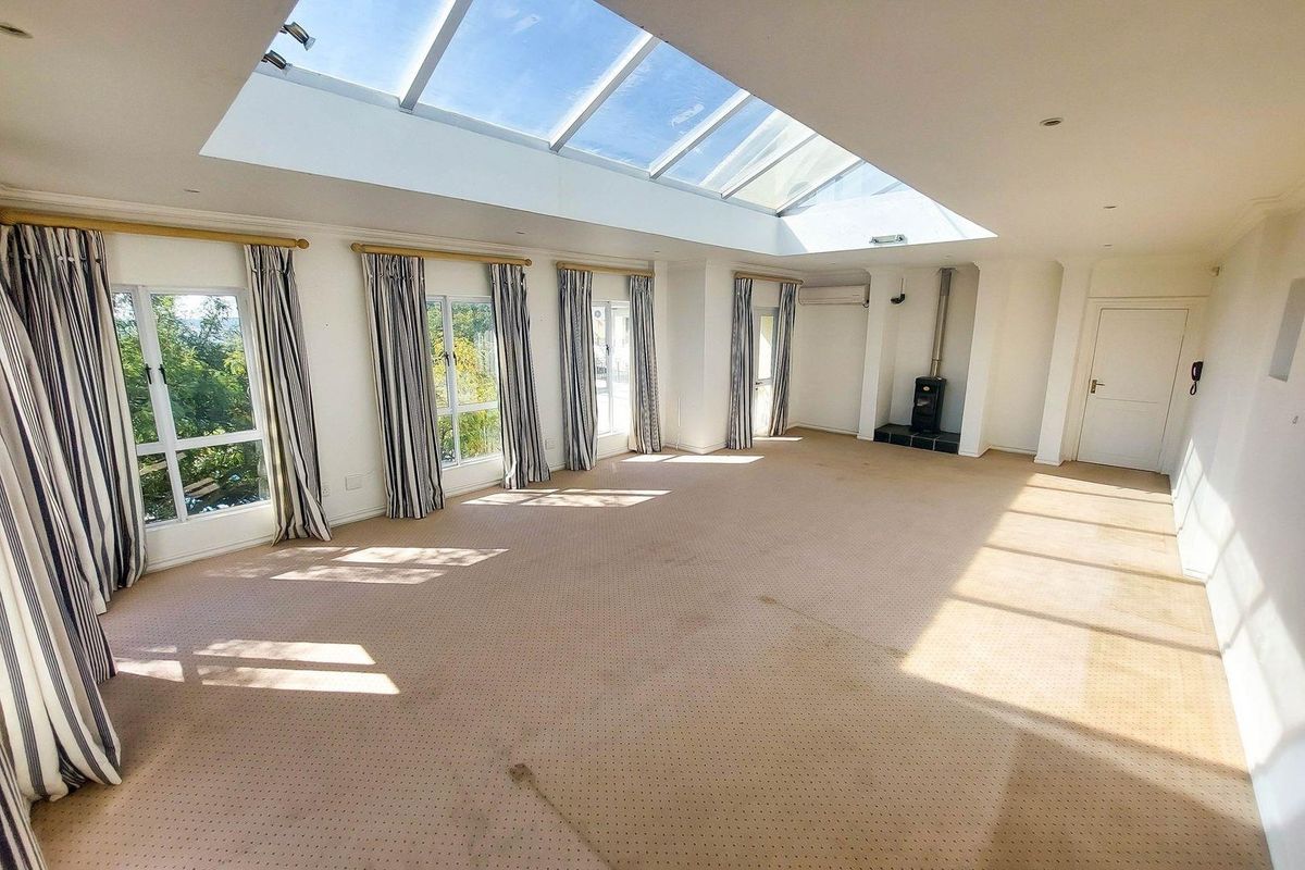 Spacious living room featuring a large skylight, wood-burning stove, and air conditioning, offering a bright and open layout.