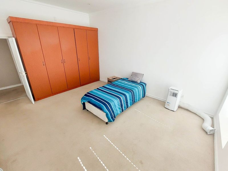 A bedroom featuring a large built-in wardrobe and carpeted flooring, offering a functional space ready for updates.
