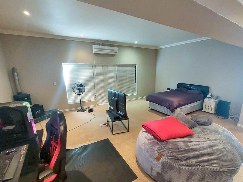 Spacious bedroom featuring neutral walls, carpet flooring, recessed downlighting, and a wall-mounted split-system air conditioner.