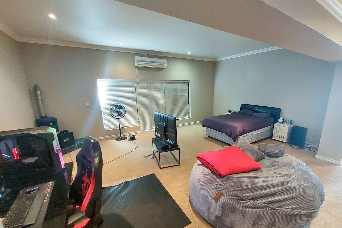 Spacious bedroom featuring neutral walls, carpet flooring, recessed downlighting, and a wall-mounted split-system air conditioner.