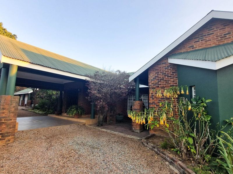Front exterior view of a brick house featuring a covered carport, pitched roof, and established garden area.