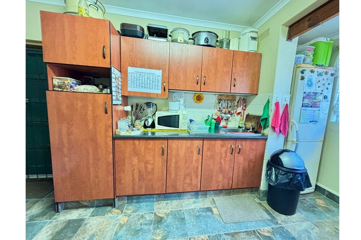 A functional kitchen area featuring wood-look laminate cabinetry, tiled splashbacks, and durable floor tiles, providing a practical workspace for daily meal preparation.
