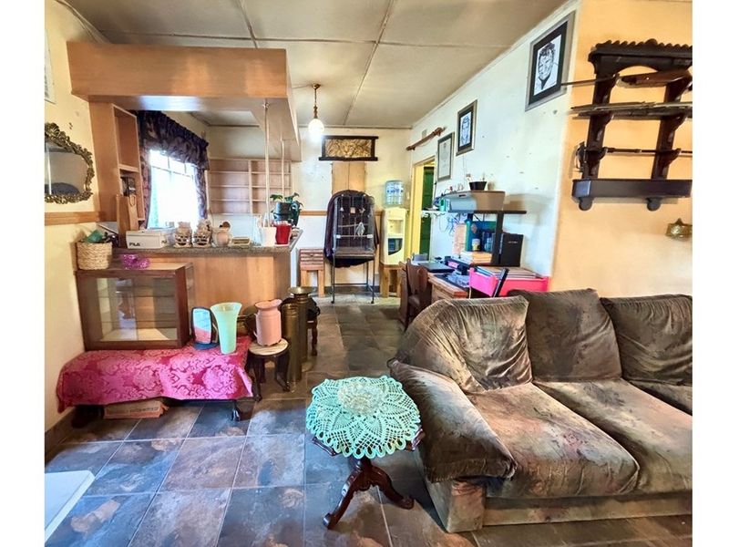 Open plan living area featuring tiled flooring and a breakfast bar counter, providing a functional space with potential for modernization.