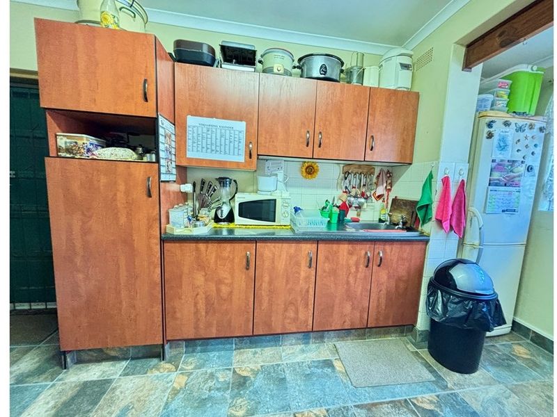 A functional kitchen area featuring wood-look laminate cabinetry, tiled splashbacks, and durable floor tiles, providing a practical workspace for daily meal preparation.