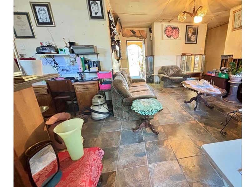 A living room area featuring tiled flooring and a ceiling light fixture, providing a functional space with potential for modernization and cosmetic updates.