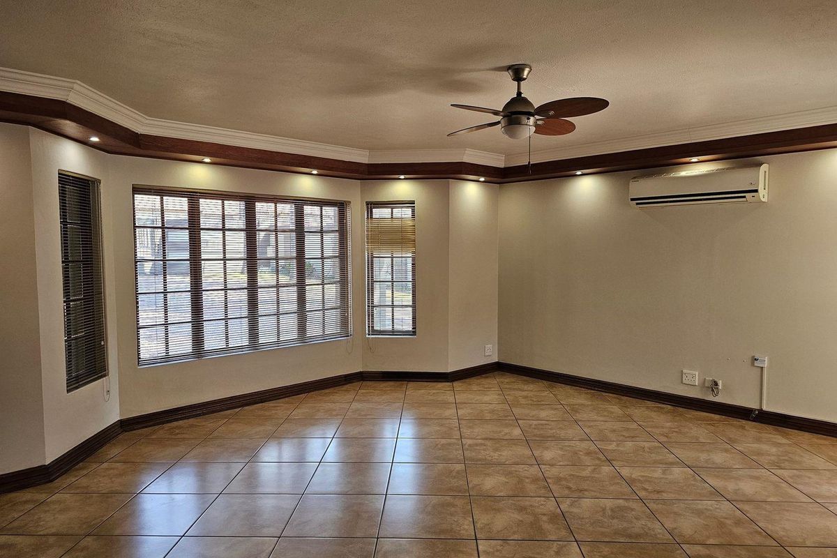Spacious living area featuring tiled flooring, recessed ceiling lighting, a ceiling fan, and a wall-mounted air conditioning unit.