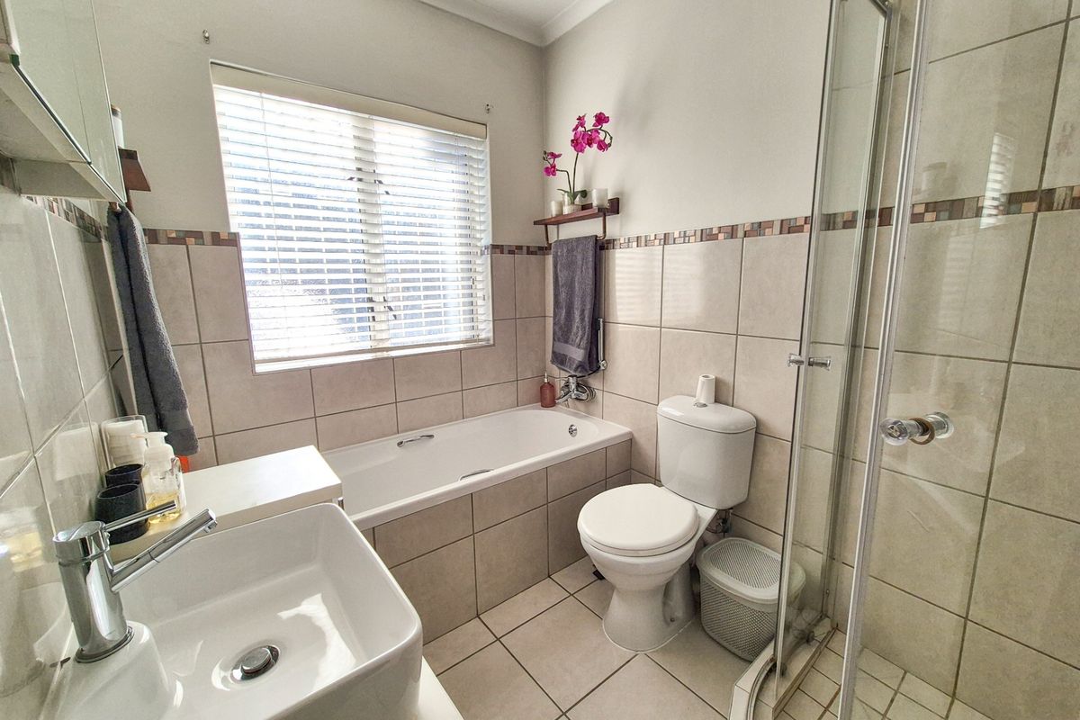 A well-maintained bathroom featuring a built-in bathtub, separate glass shower enclosure, ceramic tiling, and a modern basin with chrome fixtures.