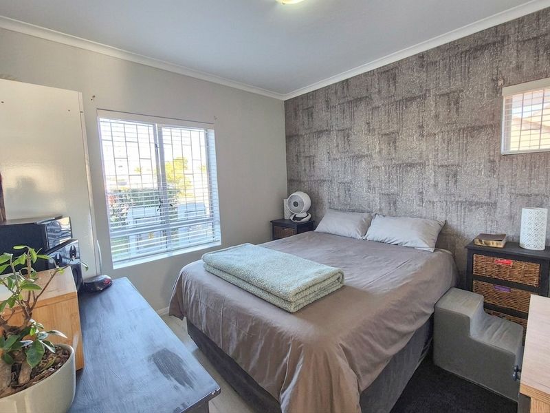 A bedroom featuring a textured accent wall, security bars on the window, and venetian blinds.