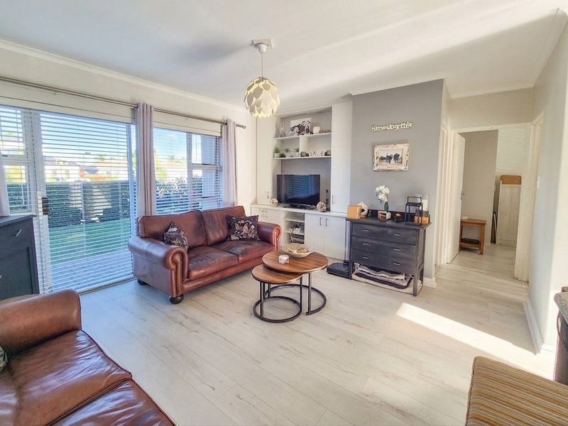 Bright living room featuring light laminate flooring, built-in shelving, and large sliding glass doors providing access to the outdoor area.