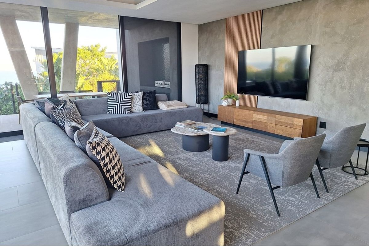 Modern living room featuring a concrete feature wall with timber accents, large format floor tiles, and expansive floor-to-ceiling sliding glass doors.