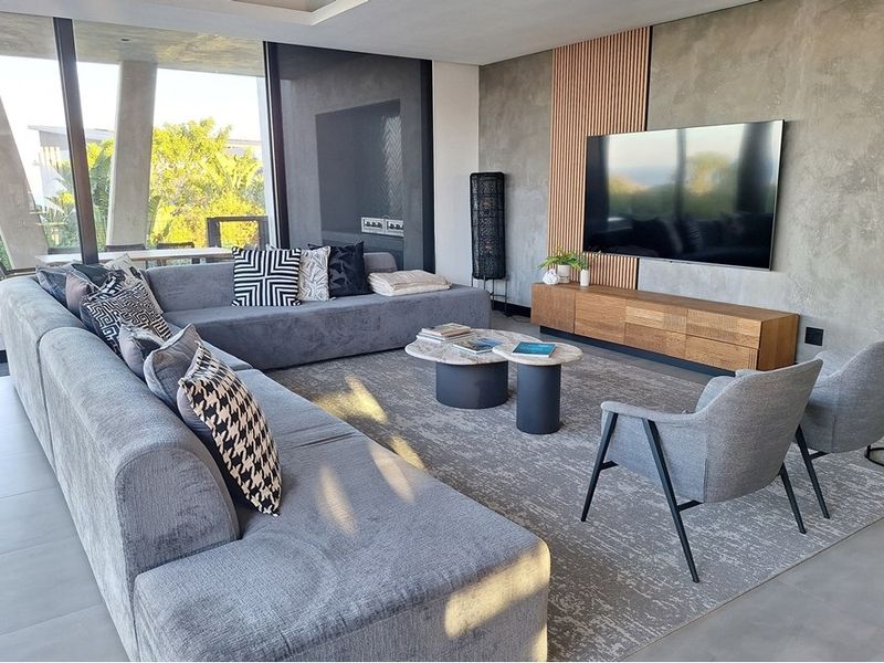 Modern living room featuring a concrete feature wall with timber accents, large format floor tiles, and expansive floor-to-ceiling sliding glass doors.