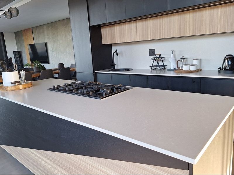 Modern open-plan kitchen featuring a large island with integrated gas cooktop, sleek matte cabinetry, and high-quality stone countertops.
