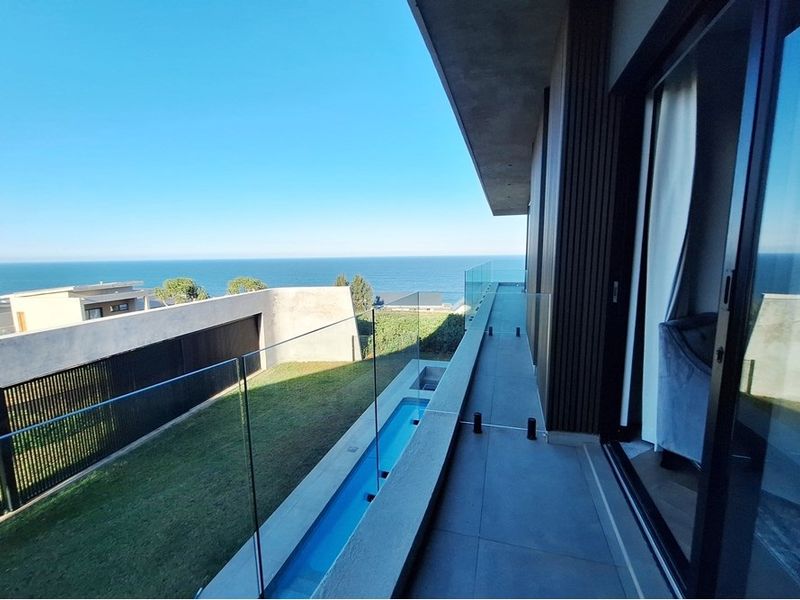 Modern balcony featuring a glass balustrade, tiled flooring, and a built-in water feature, offering expansive ocean views.