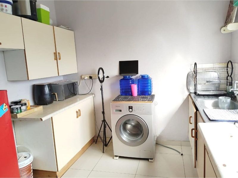 A functional kitchen area featuring laminate cabinetry, tiled flooring, and a stainless steel sink, offering a practical layout for daily use.