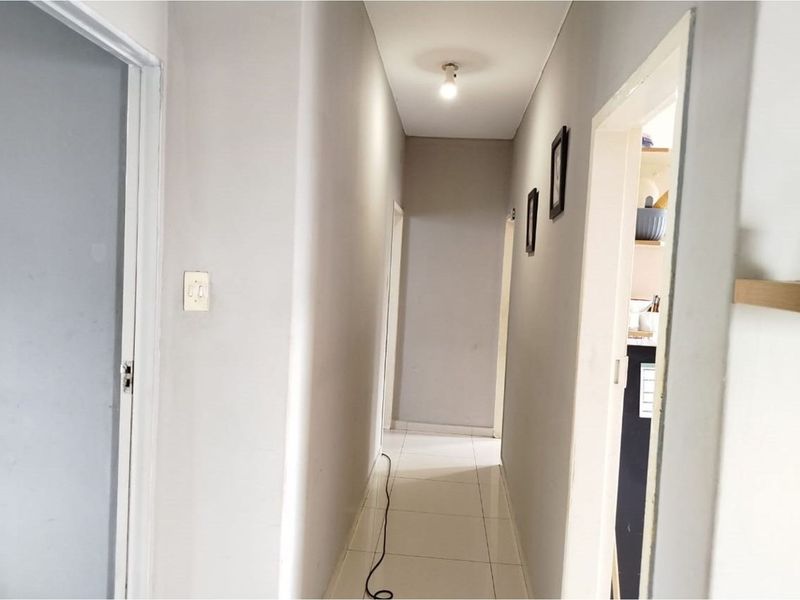 A clean and functional hallway featuring neutral wall tones and tiled flooring, providing access to various rooms within the apartment.