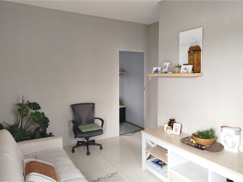 A neutrally painted living room featuring tiled flooring and a built-in wall shelf, providing a clean and functional space.