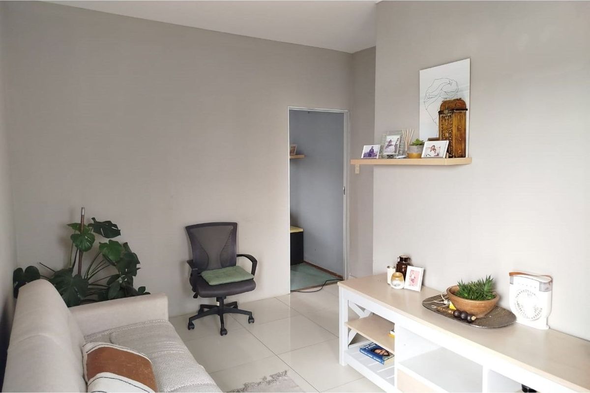 A neutrally painted living room featuring tiled flooring and a built-in wall shelf, providing a clean and functional space.