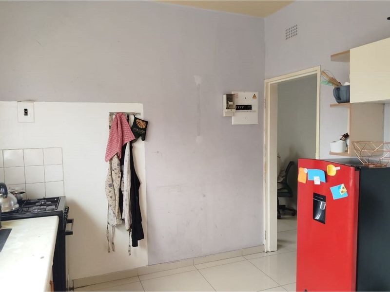 A functional kitchen area featuring tiled flooring, a gas stove, and open shelving, currently requiring cosmetic updates to the wall finishes.