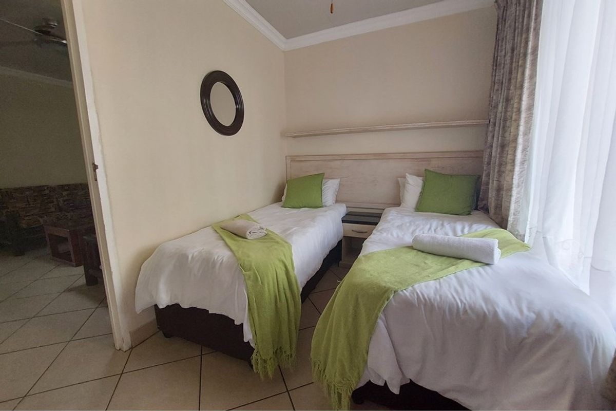 A functional bedroom featuring tiled flooring, a built-in headboard, and decorative ceiling cornicing, offering a comfortable and well-maintained space.