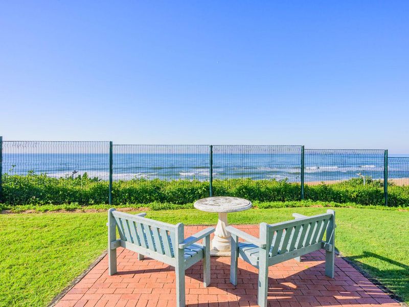 A well-maintained garden area featuring a paved patio and mesh fencing, offering direct, unobstructed views of the ocean.