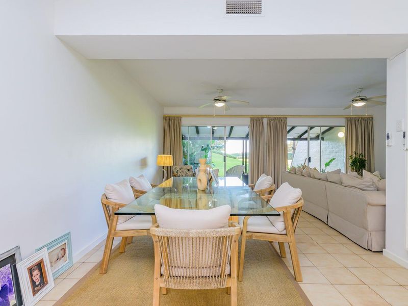 Spacious open-plan living and dining area featuring ceramic tile flooring, ceiling fans, and large sliding glass doors providing access to the outdoor patio.