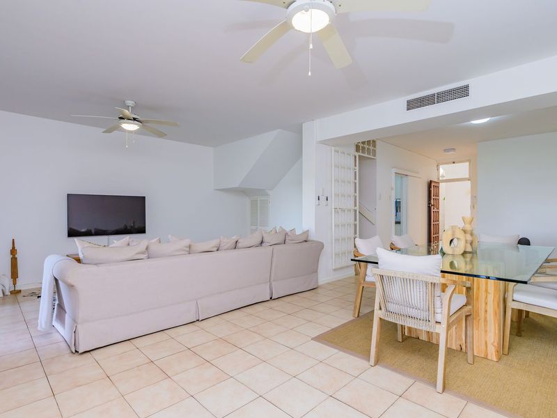 Spacious open-plan living and dining area featuring neutral ceramic floor tiles, dual ceiling fans, and integrated ducted air conditioning.