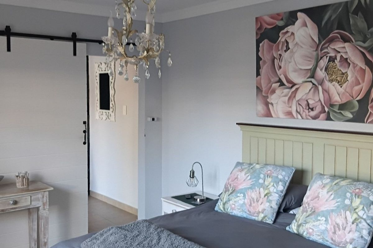 A well-maintained bedroom featuring a sliding barn door, decorative chandelier, and neutral wall finishes.