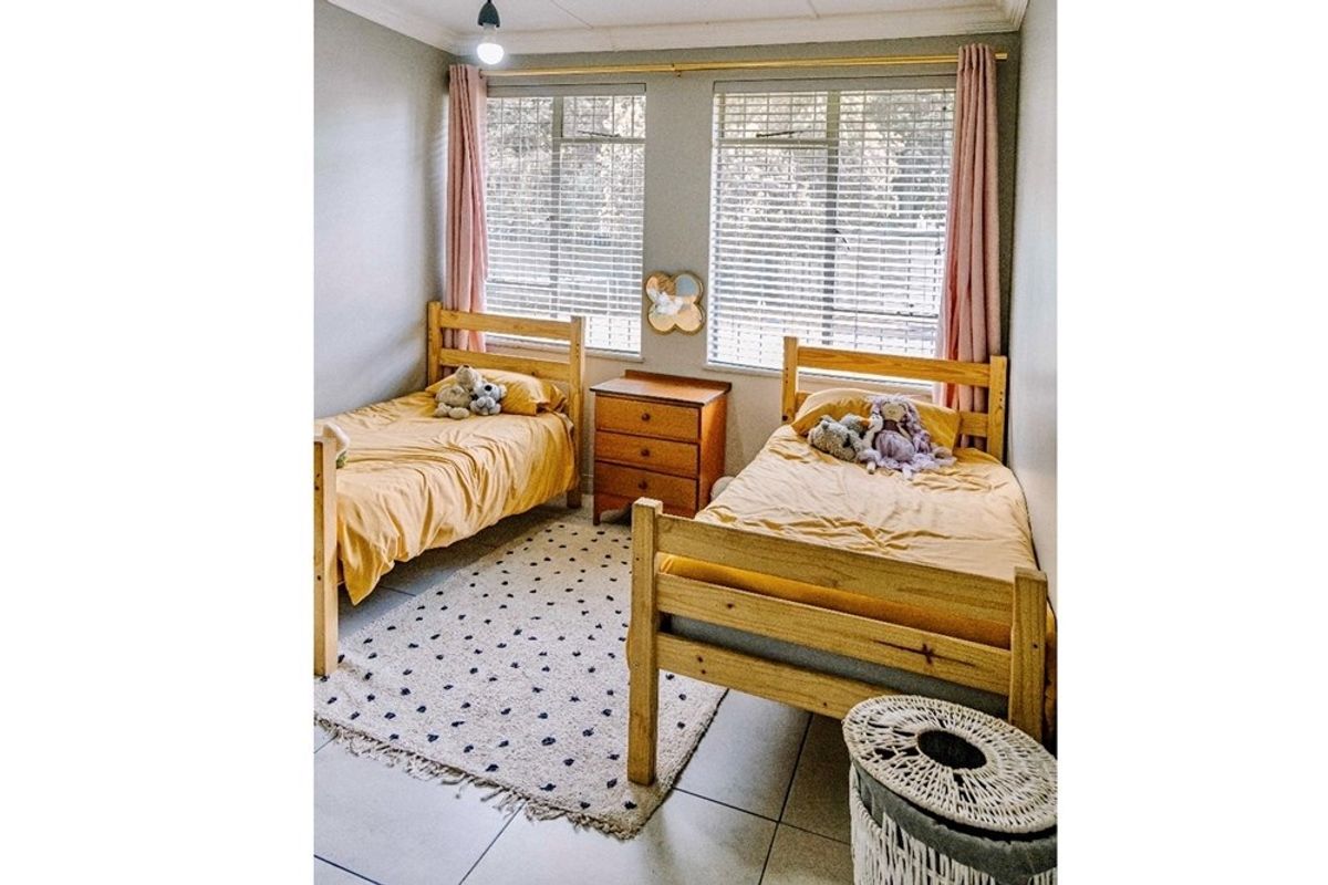 A bright bedroom featuring tiled flooring, dual windows with fitted blinds, and neutral wall finishes.