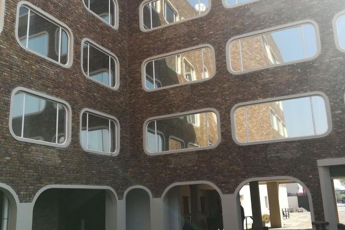 Exterior view of an apartment building featuring a brick facade with distinctive rounded rectangular windows and arched ground floor access points.
