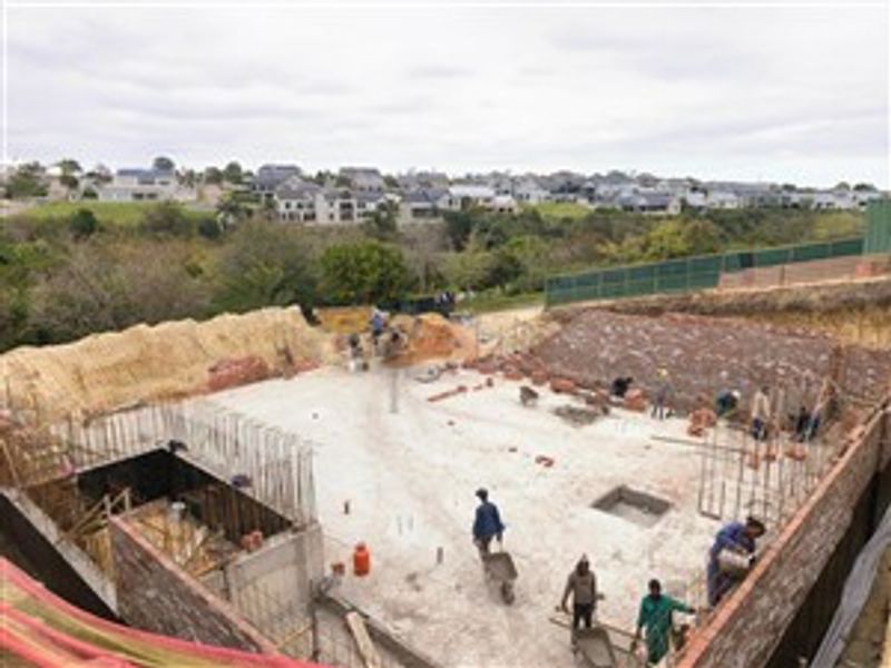 Aerial view of a residential property under construction, showing the concrete foundation, retaining walls, and ongoing site development.