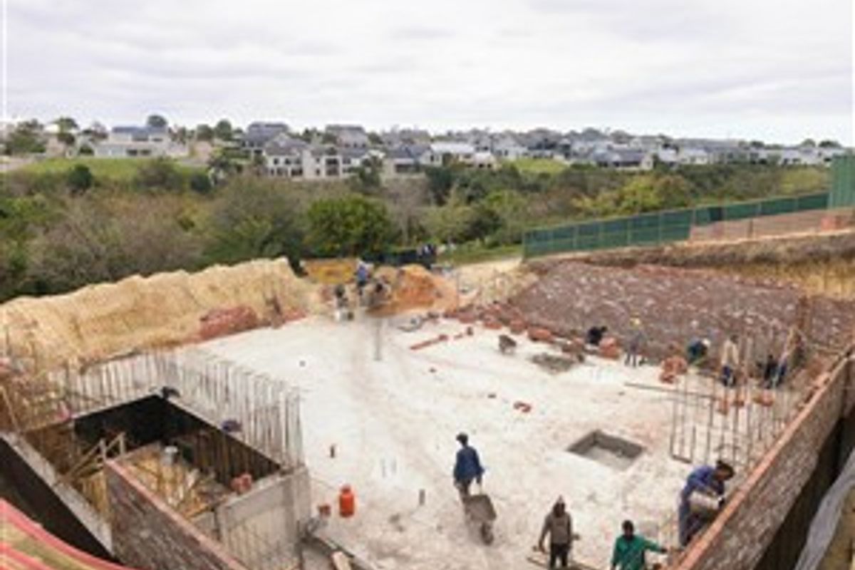Aerial view of a residential property under construction, showing the concrete foundation, retaining walls, and ongoing site development.