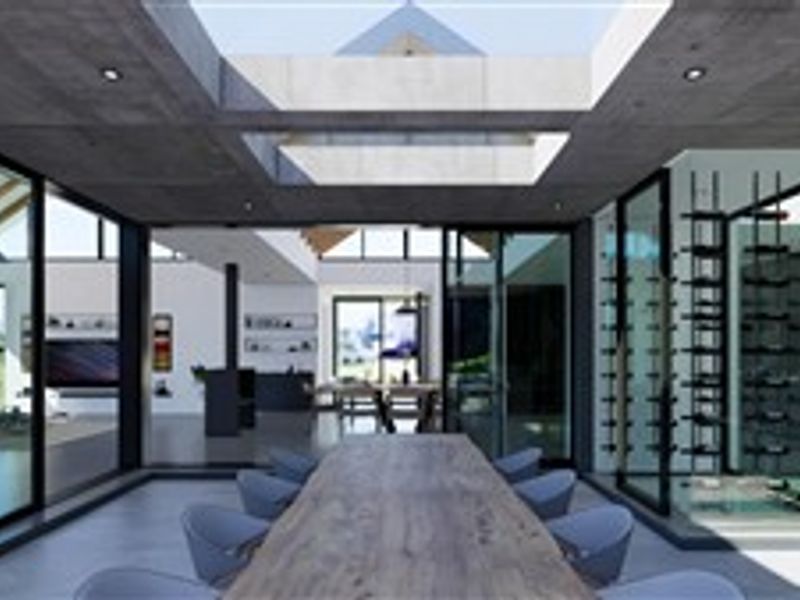 Modern open-plan living area featuring an exposed concrete ceiling, large skylight, expansive sliding glass doors, and a sophisticated glass-enclosed wine cellar.