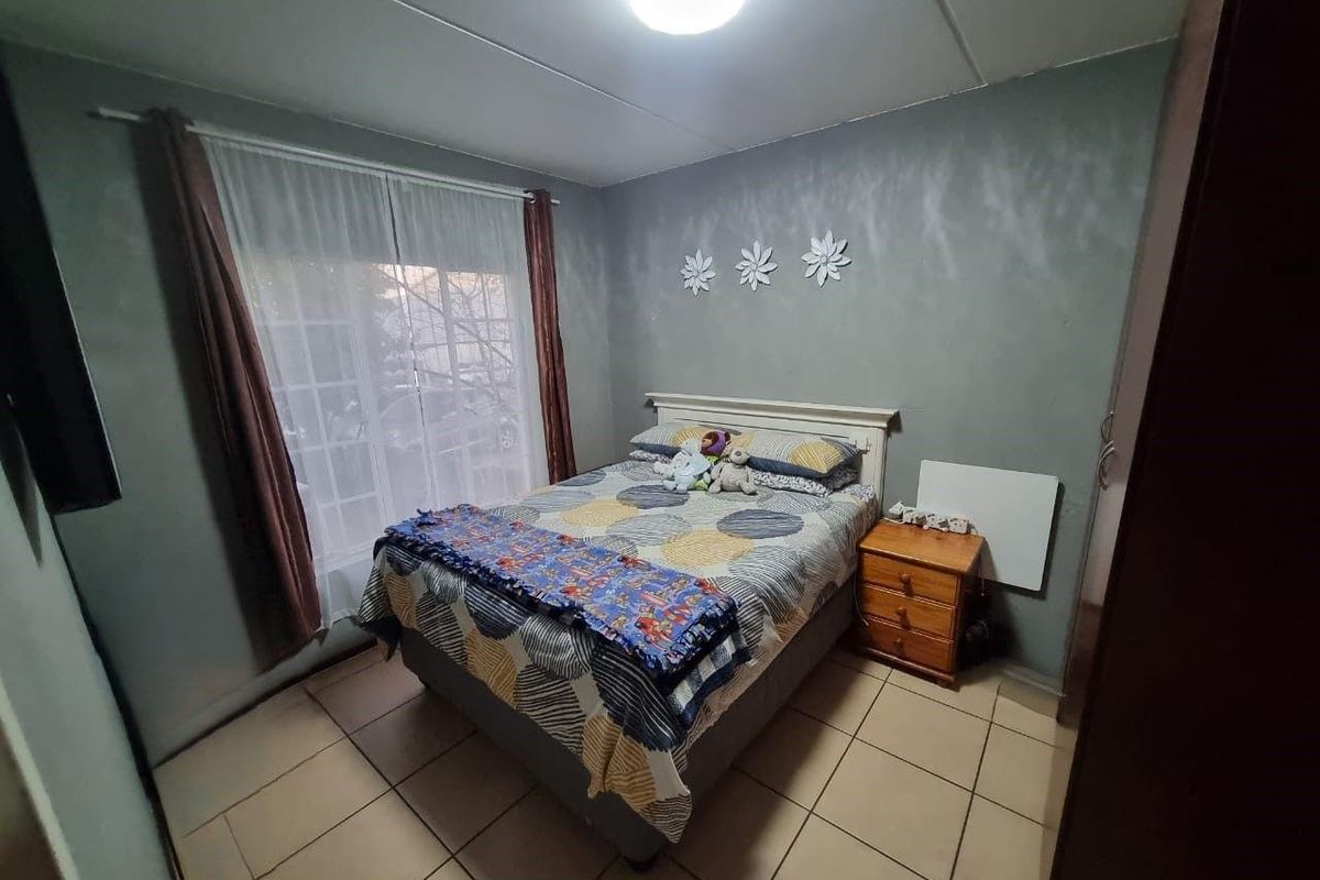 A bedroom featuring tiled flooring, a ceiling light fixture, and a sliding glass door providing natural light.