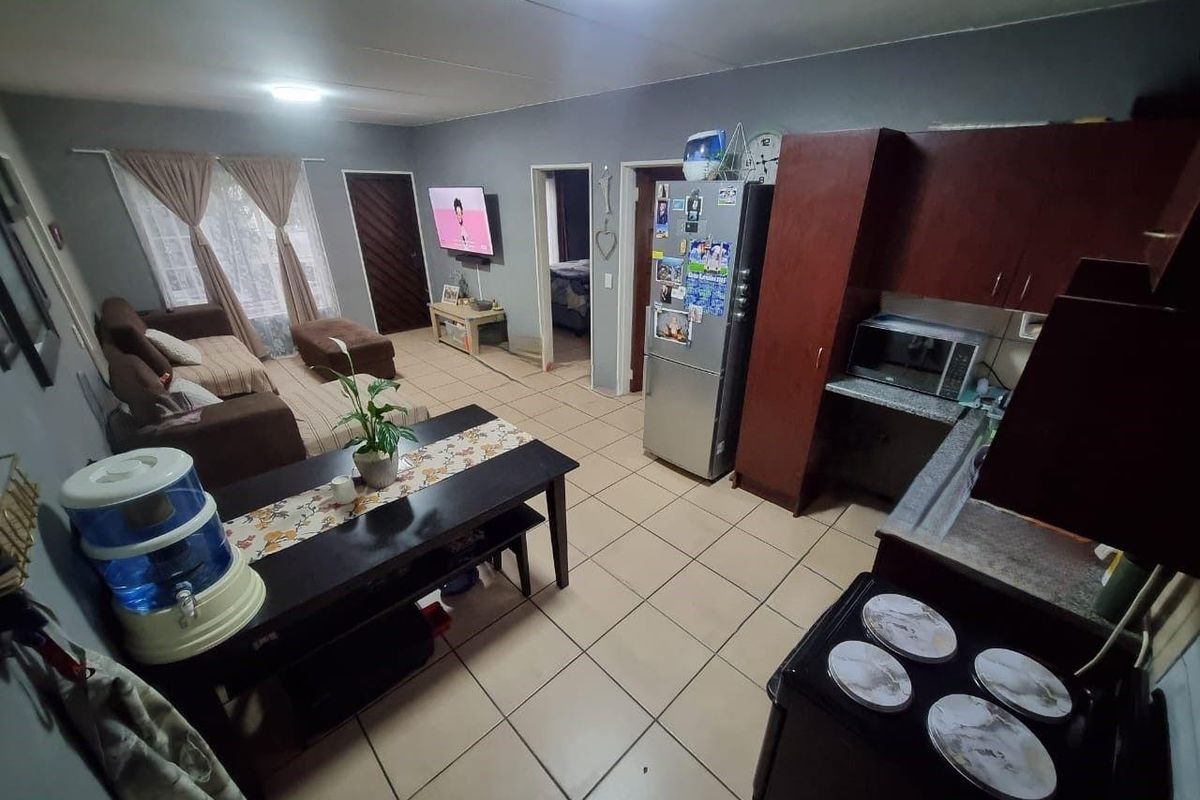 Open-plan living and kitchen area featuring ceramic tile flooring, functional cabinetry, and direct access to adjacent rooms.