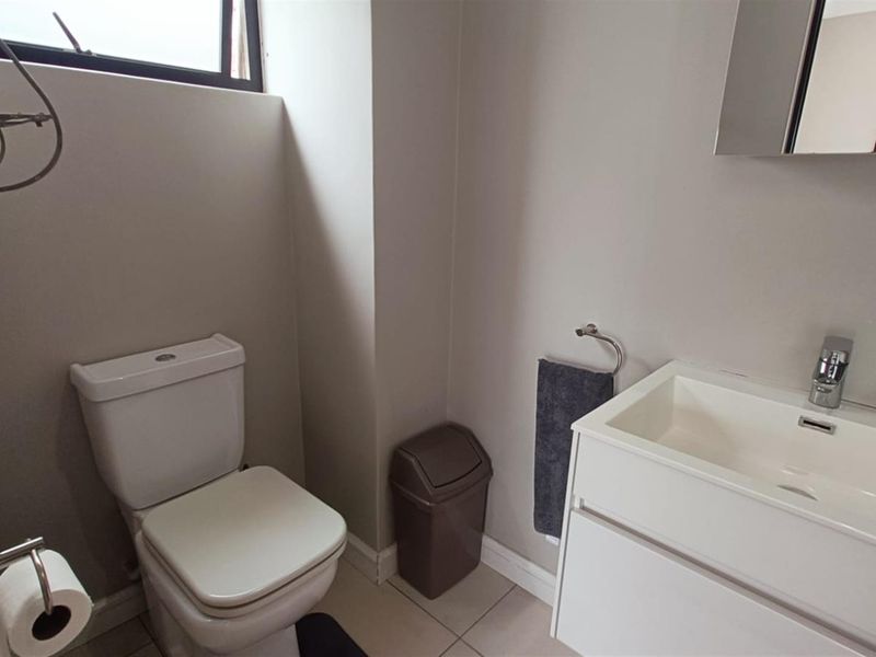 A clean and functional bathroom featuring a modern vanity with basin, toilet, and tiled flooring.