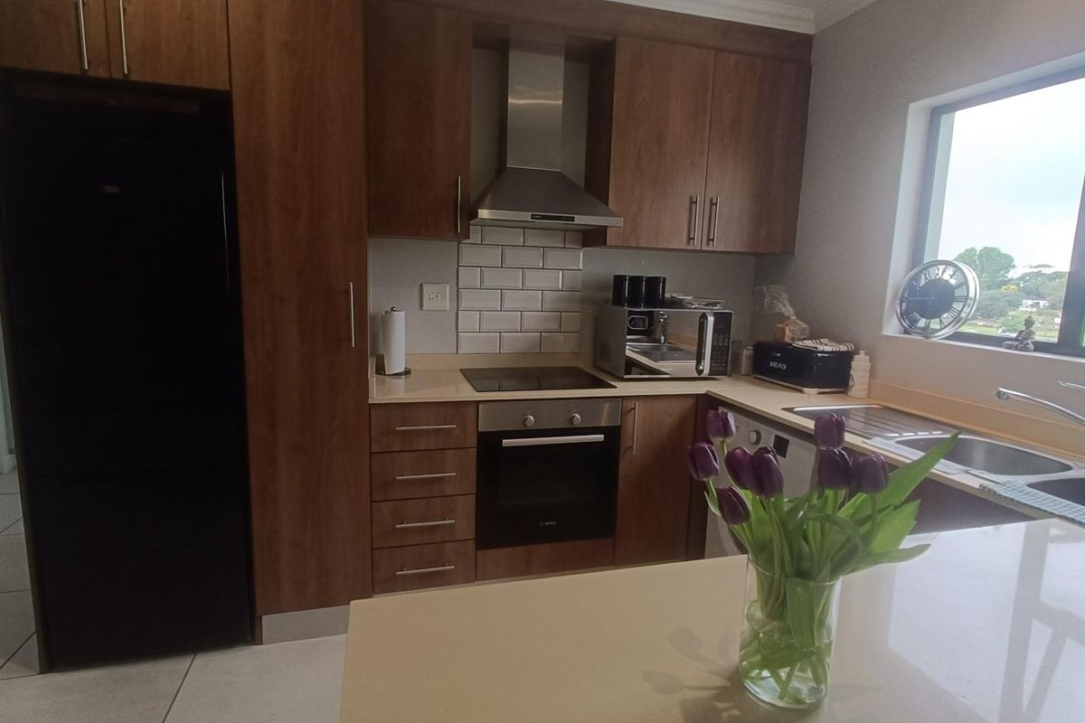 Modern kitchen featuring wood-finish cabinetry, stone countertops, subway tile backsplash, and integrated stainless steel appliances including an oven and hob.