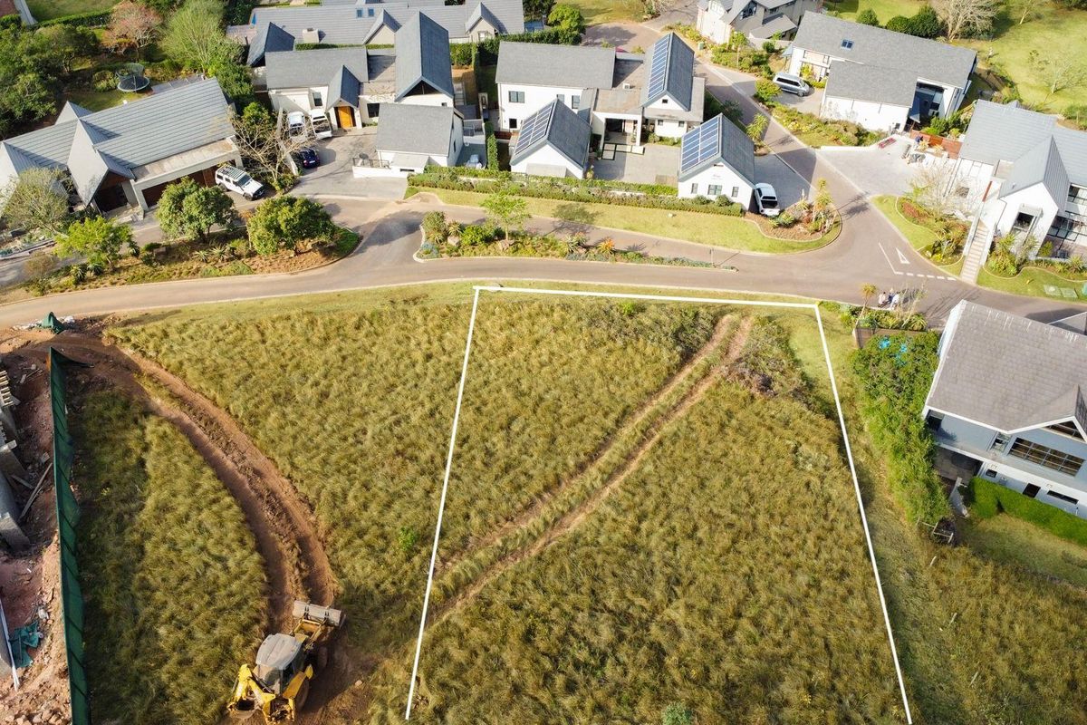 An aerial view of a vacant residential plot in a developed estate, featuring marked boundaries and surrounding established homes.