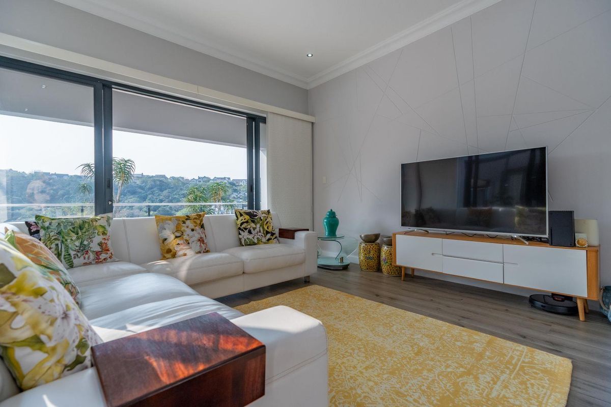 Modern living room featuring large sliding glass doors that open to a balcony with scenic views and decorative wall paneling.
