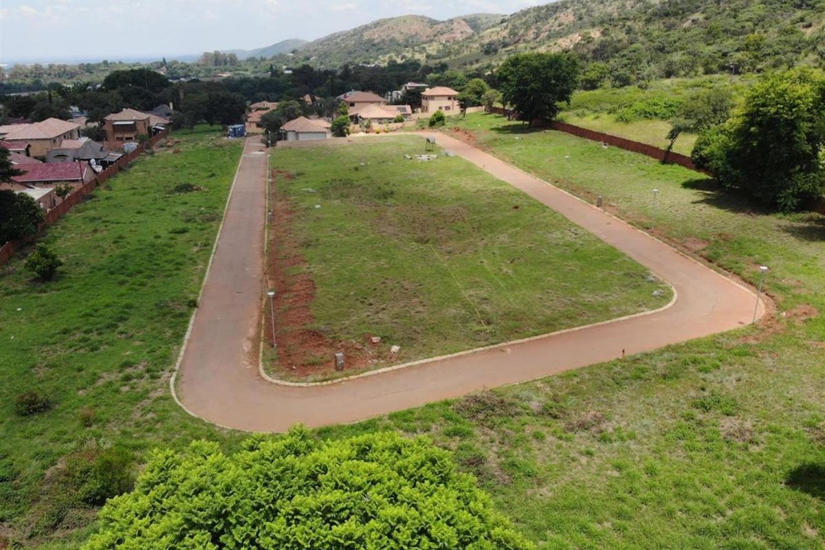 An aerial view of a vacant residential plot featuring established paved road access and surrounding neighborhood infrastructure.