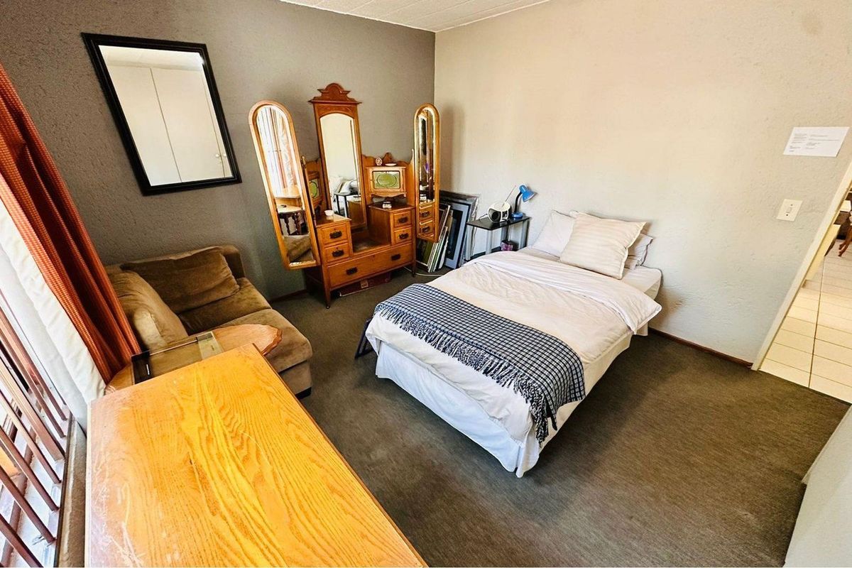 A bedroom featuring carpeted flooring, neutral wall finishes, and a window with curtains.