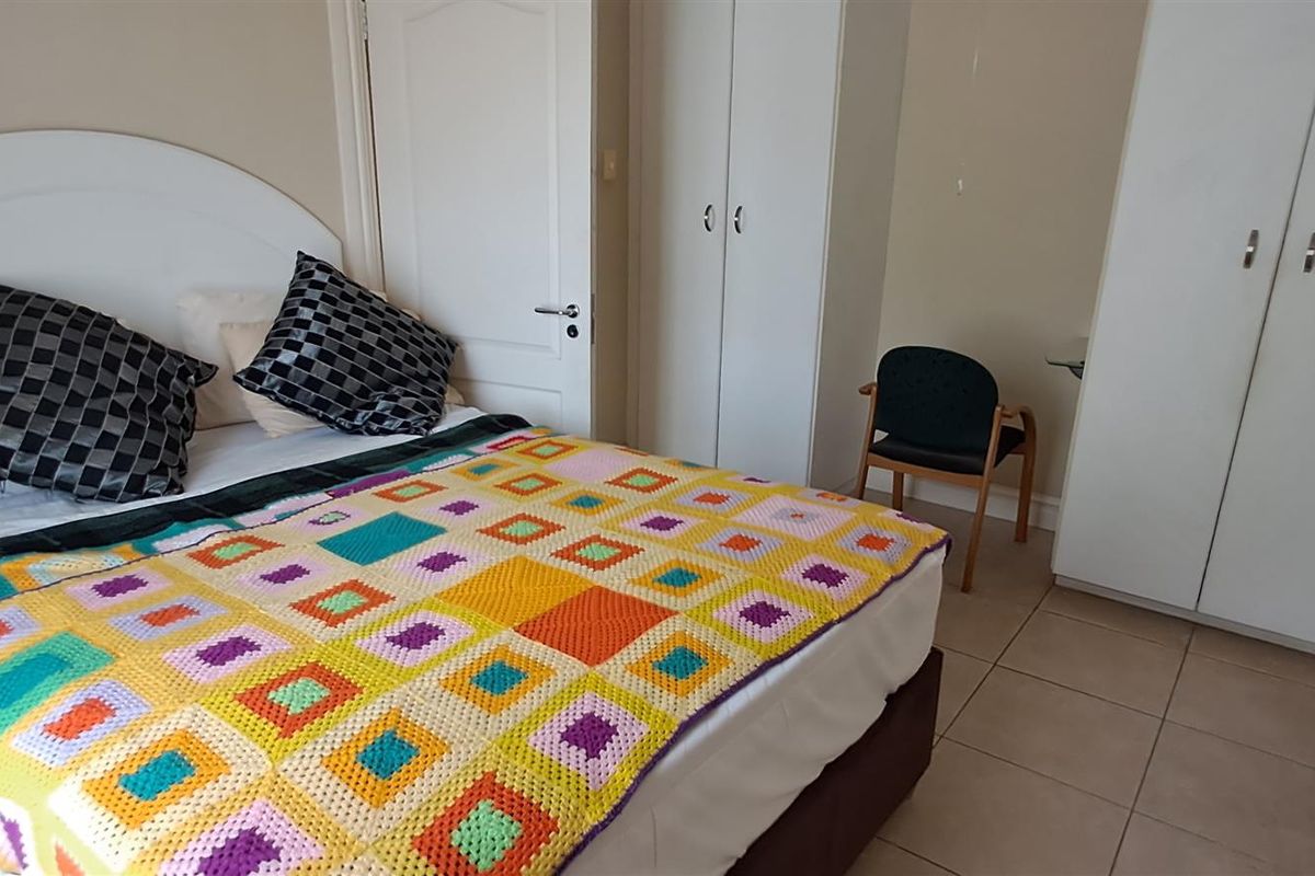 A functional bedroom featuring tiled flooring and built-in white wardrobes, providing ample storage space within a neutral interior setting.