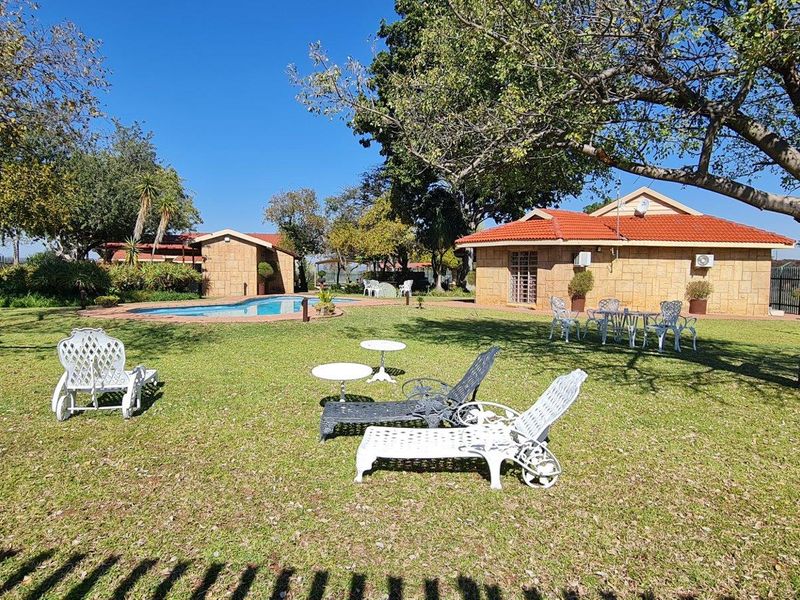 Spacious farm garden featuring a swimming pool, mature trees, and well-maintained lawn area surrounding the residential buildings.
