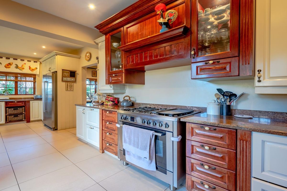 A spacious kitchen featuring a mix of dark wood and cream cabinetry, granite countertops, and a stainless steel gas range with an integrated oven.
