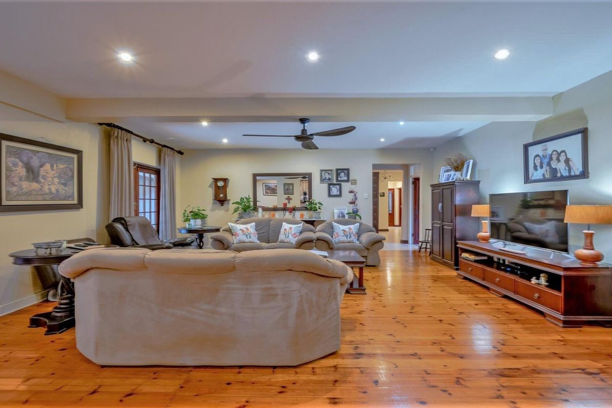 Spacious living room featuring polished timber flooring, recessed downlighting, and a ceiling fan, providing a warm and inviting atmosphere.
