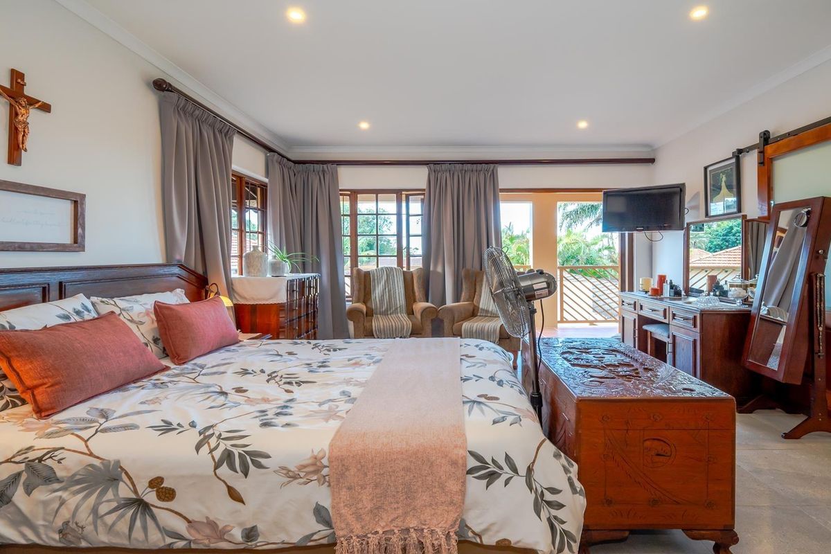 Spacious bedroom featuring tiled flooring, recessed lighting, and a sliding barn door leading to an en-suite bathroom, with direct access to a private balcony.