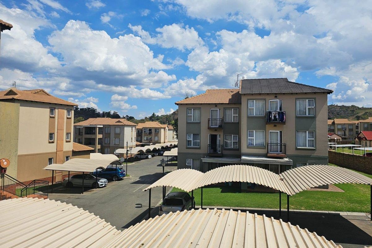 An elevated view of the townhouse complex featuring multiple residential blocks, paved driveways, and covered carport parking structures.