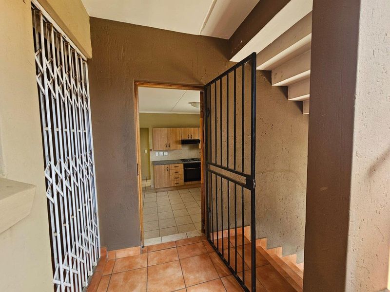 Entrance area featuring tiled flooring, a security gate, and a staircase, providing direct access to the kitchen area.
