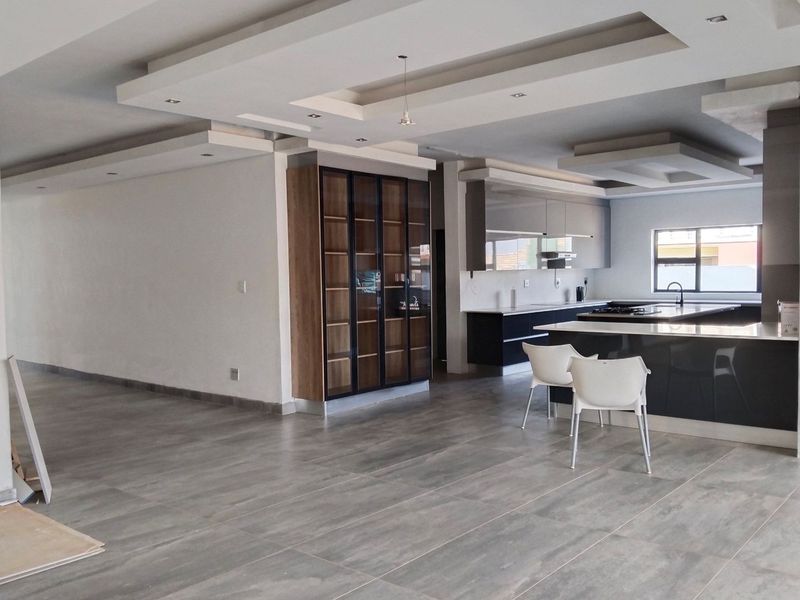 Spacious open-plan living and kitchen area featuring modern cabinetry, a large kitchen island with stone countertops, and contemporary recessed ceiling details.
